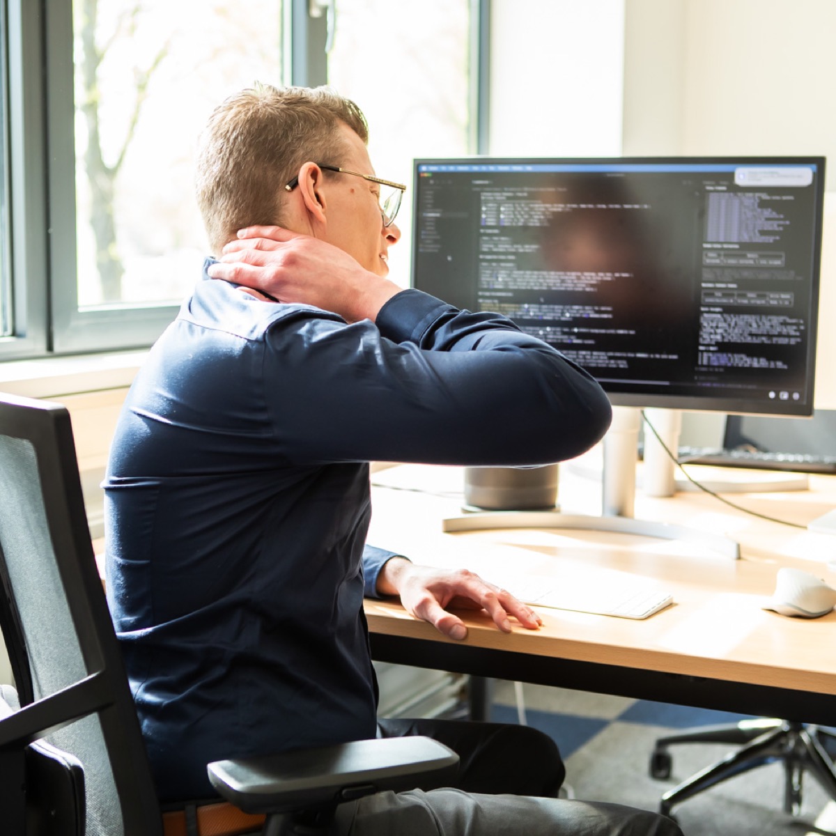 Man met nekklachten achter zijn bureau